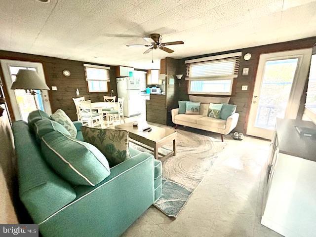 living room featuring ceiling fan and wood walls