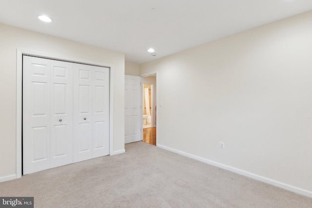 unfurnished bedroom with light colored carpet and a closet