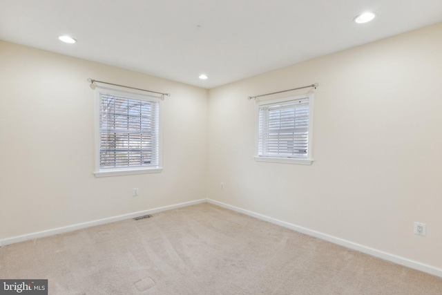 spare room featuring light colored carpet and a healthy amount of sunlight