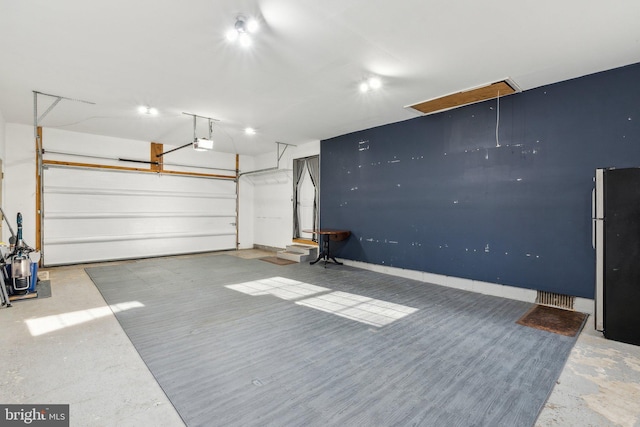 garage featuring a garage door opener and stainless steel refrigerator