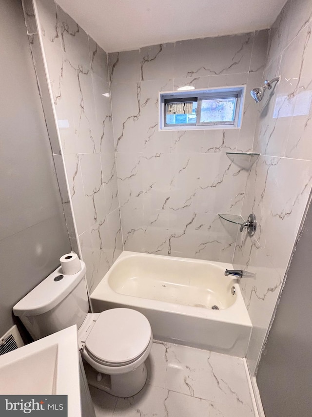 bathroom featuring tiled shower / bath combo and toilet