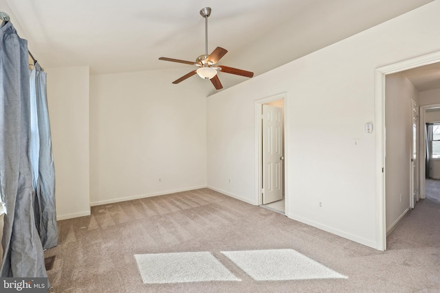 empty room with ceiling fan, vaulted ceiling, and light carpet