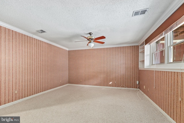 empty room featuring ceiling fan, ornamental molding, carpet, and a textured ceiling