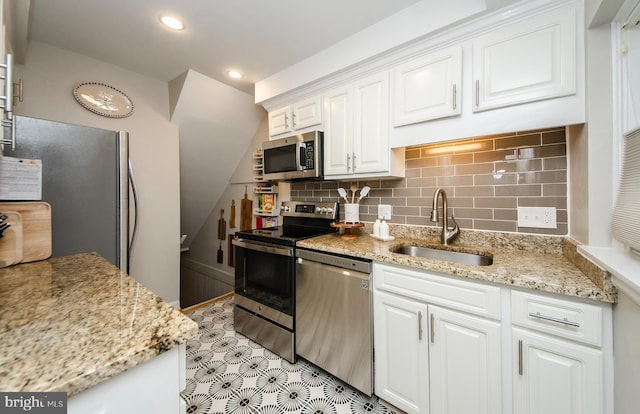 kitchen featuring light stone countertops, backsplash, stainless steel appliances, sink, and white cabinetry