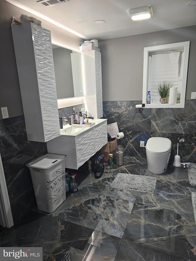 bathroom featuring vanity, toilet, and tile walls