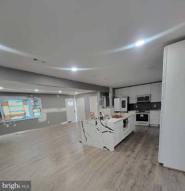 kitchen featuring decorative backsplash, stainless steel appliances, white cabinetry, light hardwood / wood-style floors, and a kitchen island