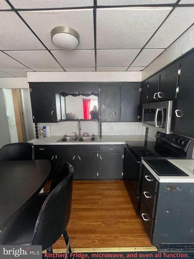 kitchen with electric range, a drop ceiling, sink, and hardwood / wood-style floors