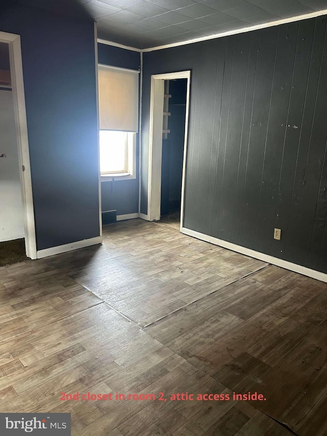 unfurnished room featuring wood-type flooring and wooden walls