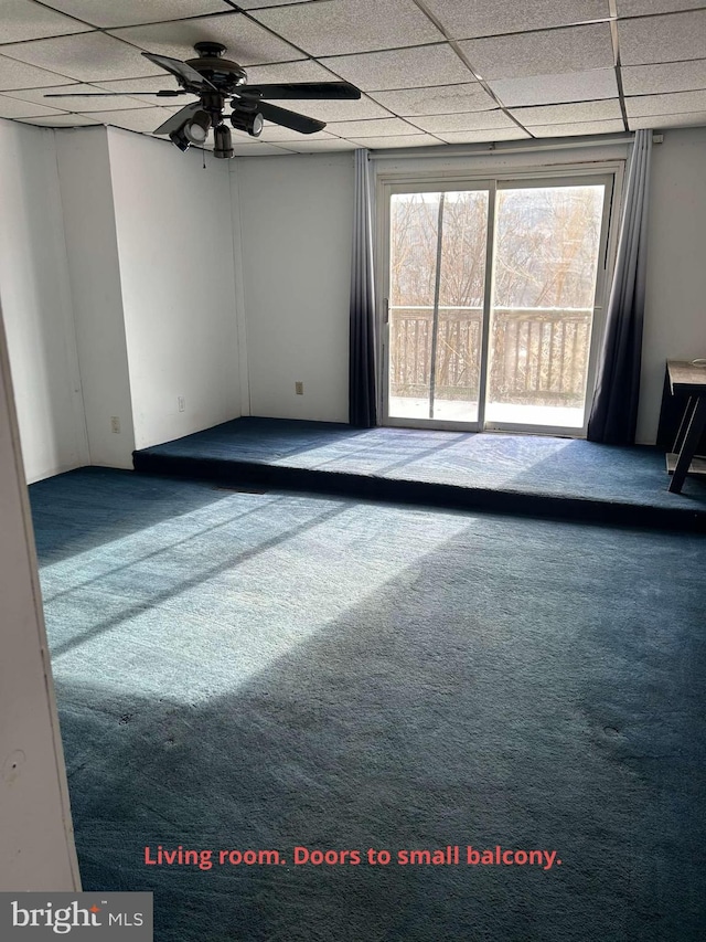 carpeted spare room with ceiling fan and a drop ceiling