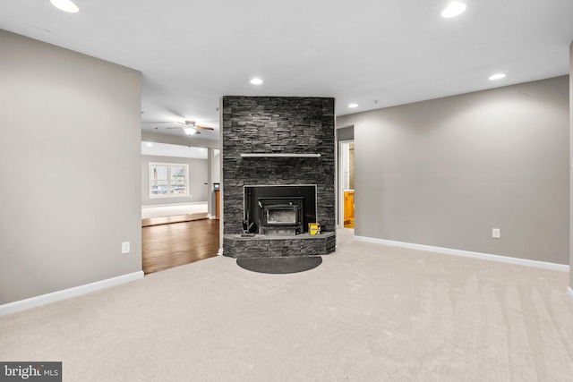 carpeted living room featuring a wood stove and ceiling fan