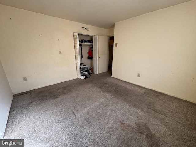 unfurnished bedroom featuring dark carpet and a closet