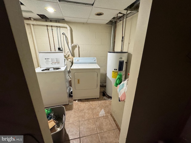 washroom featuring washing machine and dryer, electric water heater, and light tile patterned floors