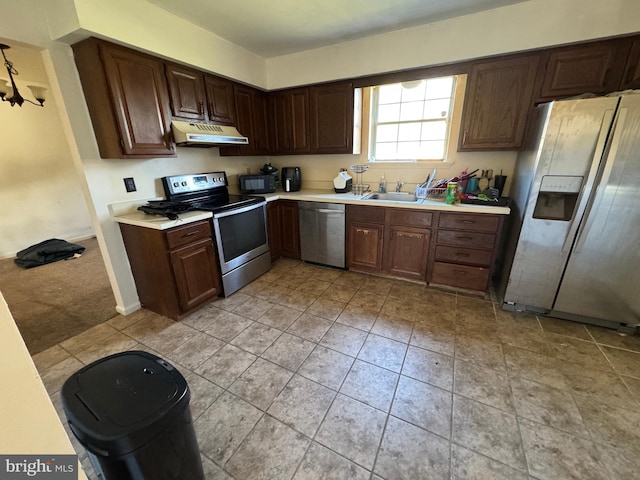 kitchen featuring dark brown cabinets, stainless steel appliances, light colored carpet, and sink