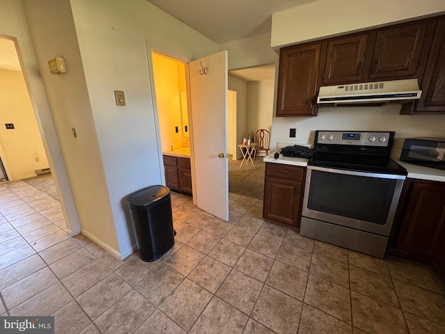 kitchen with stainless steel electric range, light tile patterned flooring, and dark brown cabinets