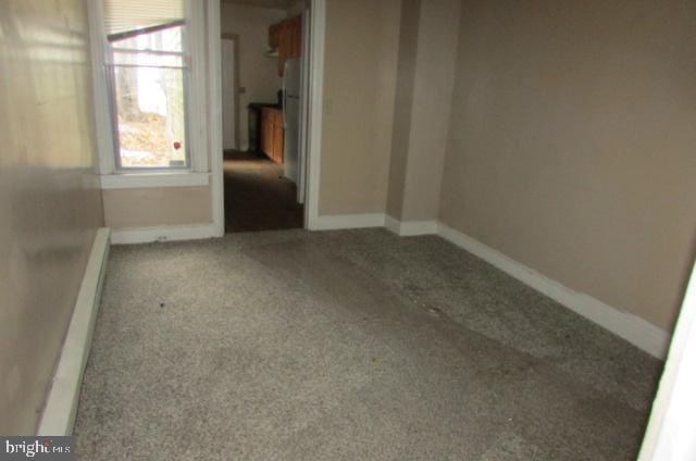 carpeted spare room with a baseboard heating unit