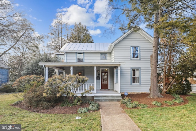 view of front of house with metal roof, a porch, and a front yard