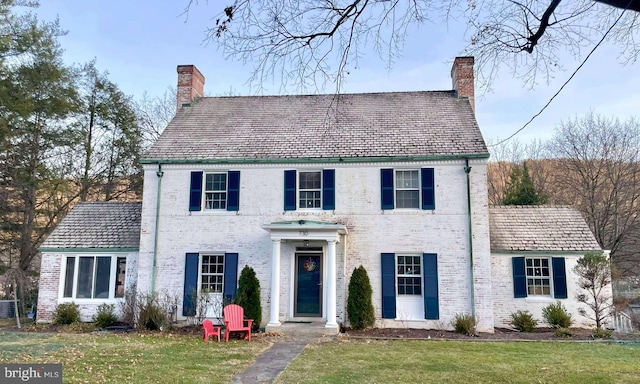 colonial home with central AC unit and a front yard