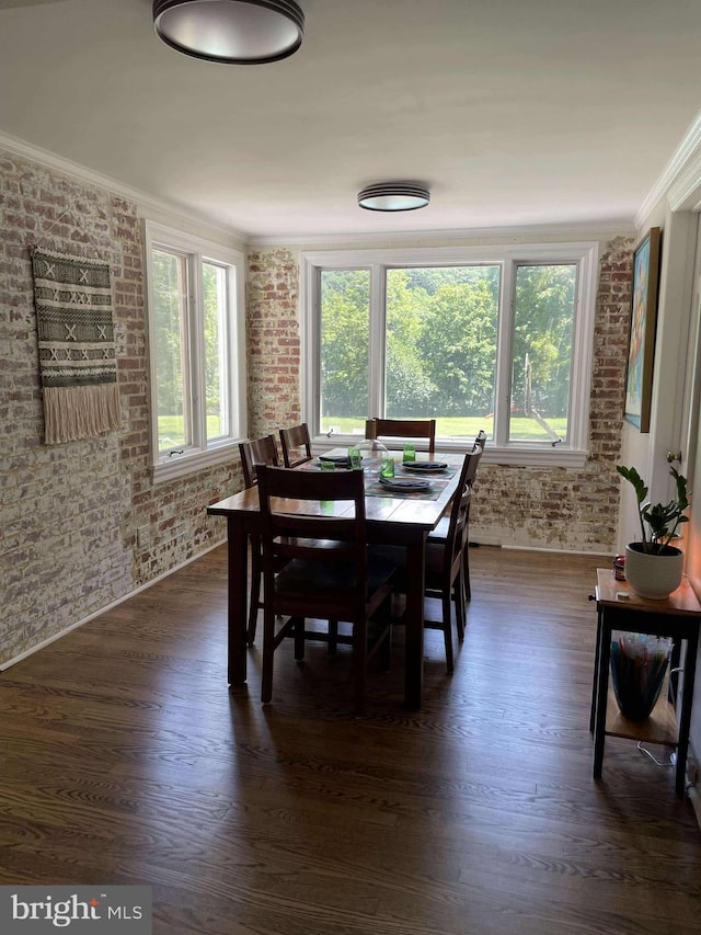 dining space with dark hardwood / wood-style flooring, ornamental molding, and brick wall