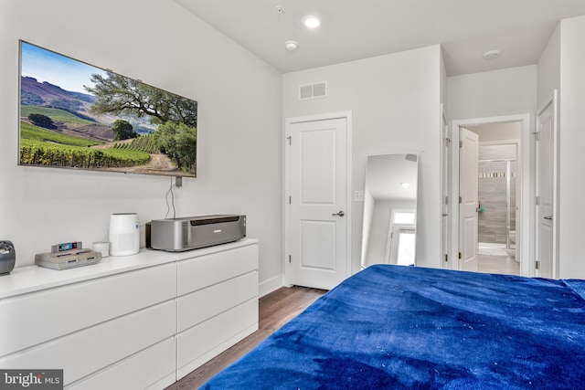 bedroom featuring ensuite bath and dark hardwood / wood-style floors