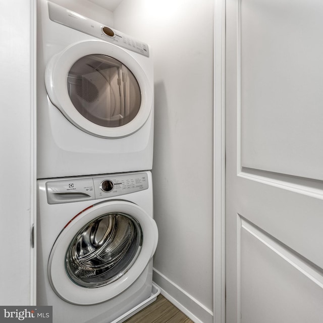 laundry room with dark hardwood / wood-style floors and stacked washer / drying machine