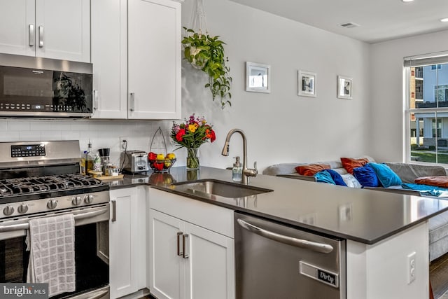 kitchen featuring kitchen peninsula, stainless steel appliances, white cabinetry, and sink