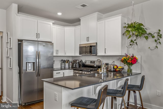 kitchen featuring kitchen peninsula, appliances with stainless steel finishes, and white cabinets