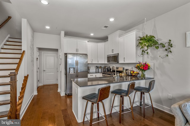 kitchen featuring white cabinets, stainless steel appliances, kitchen peninsula, and sink