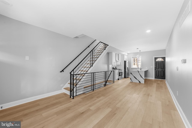 unfurnished living room with light hardwood / wood-style floors and sink