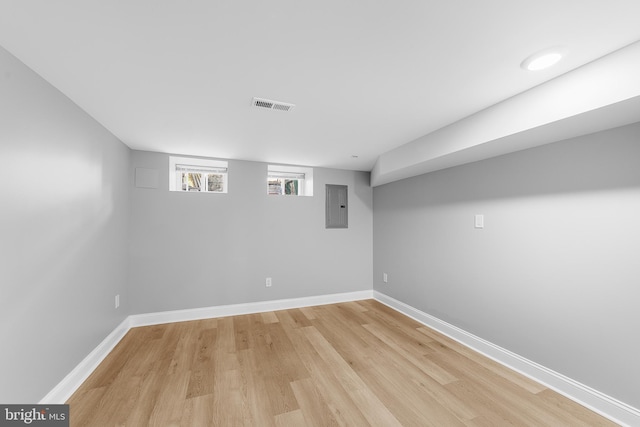 basement with electric panel and light hardwood / wood-style flooring