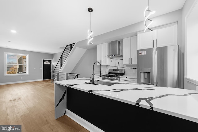 kitchen with white cabinets, pendant lighting, stainless steel appliances, and wall chimney exhaust hood