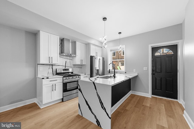 kitchen with kitchen peninsula, appliances with stainless steel finishes, white cabinets, and wall chimney exhaust hood