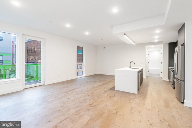 kitchen featuring sink, an island with sink, light hardwood / wood-style flooring, and appliances with stainless steel finishes