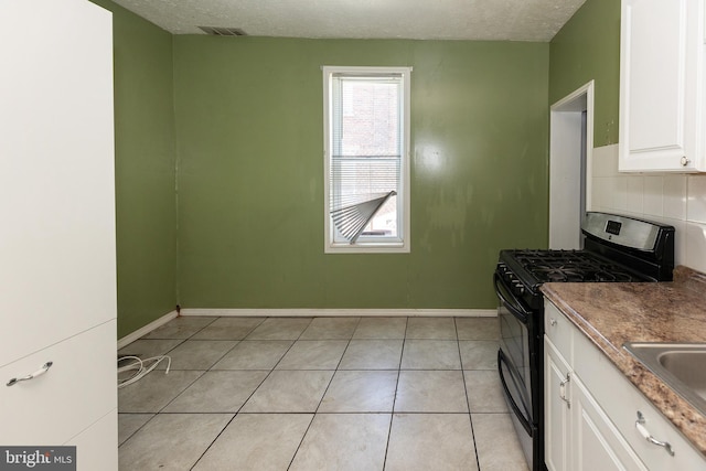 1137 Sycamore St, Camden, NJ 08103 - kitchen with range with gas cooktop, white cabinetry, light tile patterned flooring, a textured ceiling, and baseboards