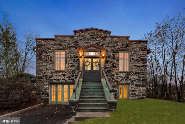 view of front of home featuring a lawn and french doors