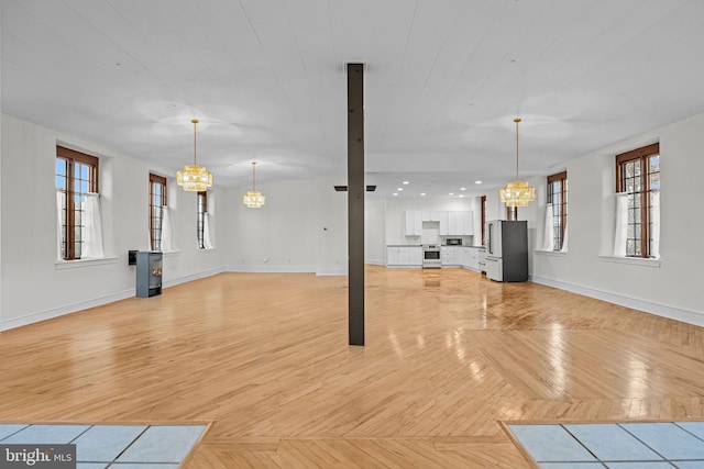 unfurnished living room featuring light parquet floors and a notable chandelier