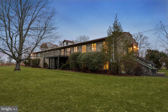 property exterior at dusk featuring a wooden deck and a yard