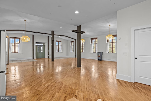 unfurnished living room featuring light hardwood / wood-style floors, an inviting chandelier, and lofted ceiling