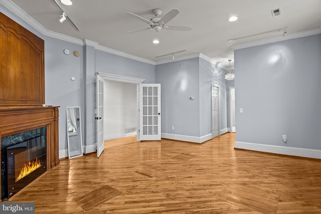 unfurnished living room featuring a high end fireplace, rail lighting, ceiling fan with notable chandelier, and ornamental molding