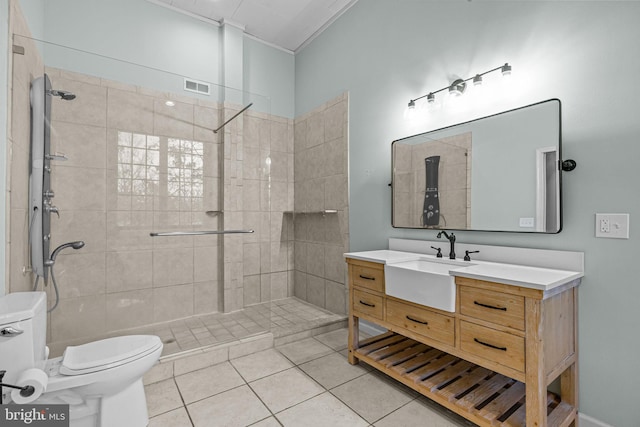 bathroom featuring toilet, tile patterned flooring, vanity, and tiled shower