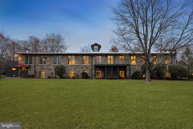 back house at dusk with a lawn