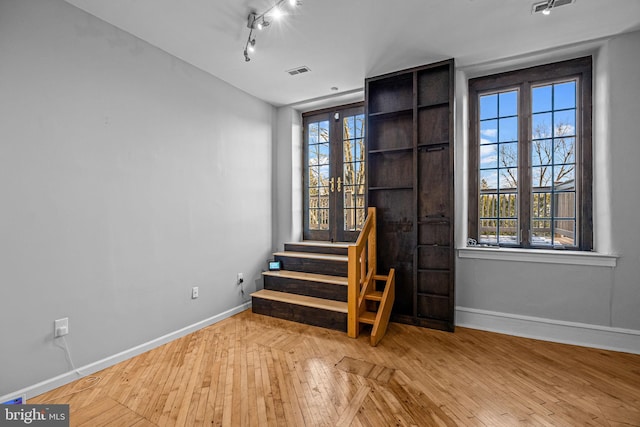 spare room with hardwood / wood-style flooring, rail lighting, and french doors