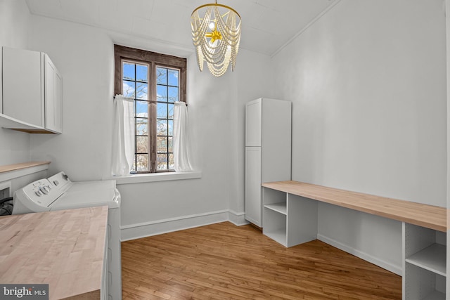 washroom with cabinets, washing machine and dryer, light hardwood / wood-style flooring, and a notable chandelier