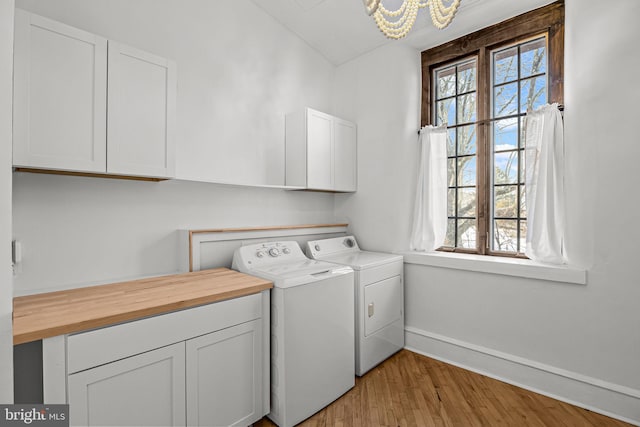 washroom featuring cabinets, light wood-type flooring, washing machine and dryer, and a chandelier