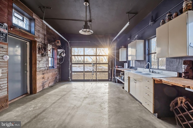 kitchen featuring decorative light fixtures, wood counters, white cabinetry, and sink