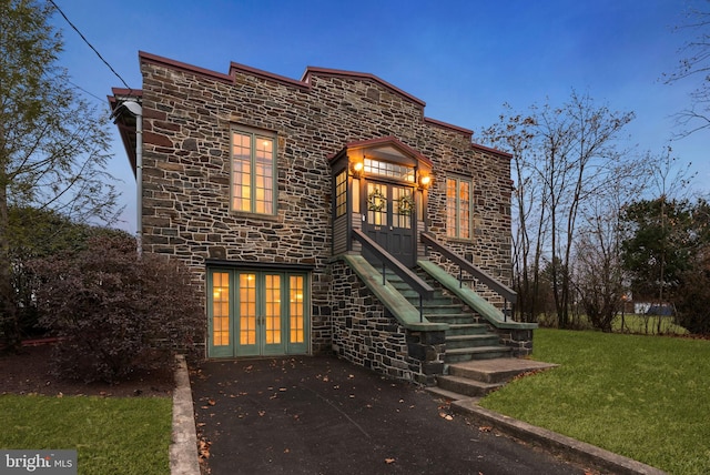 view of front of home with french doors and a lawn