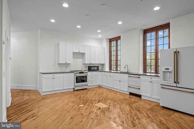 kitchen featuring sink, white cabinets, and white appliances