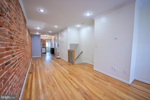 unfurnished room with light hardwood / wood-style flooring, brick wall, and ornamental molding