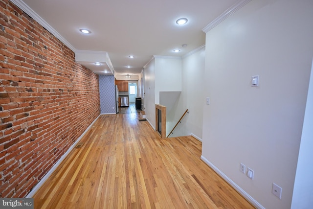 hallway featuring light wood-type flooring, crown molding, and brick wall