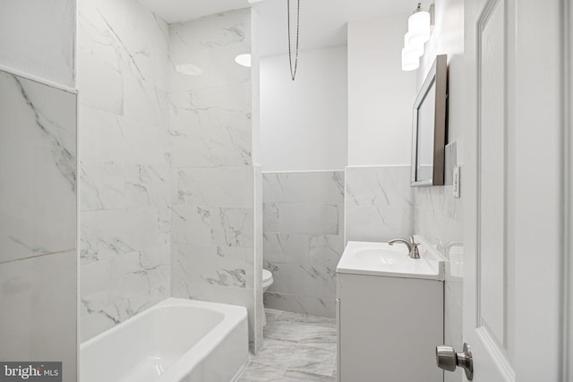 full bathroom with tiled shower / bath, vanity, toilet, and tile walls