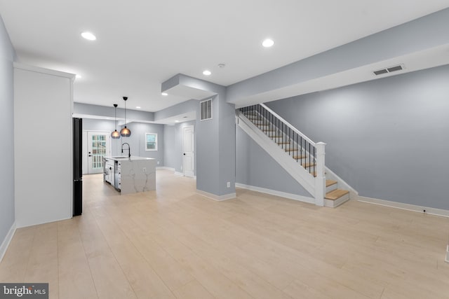 unfurnished living room with light wood-type flooring and sink